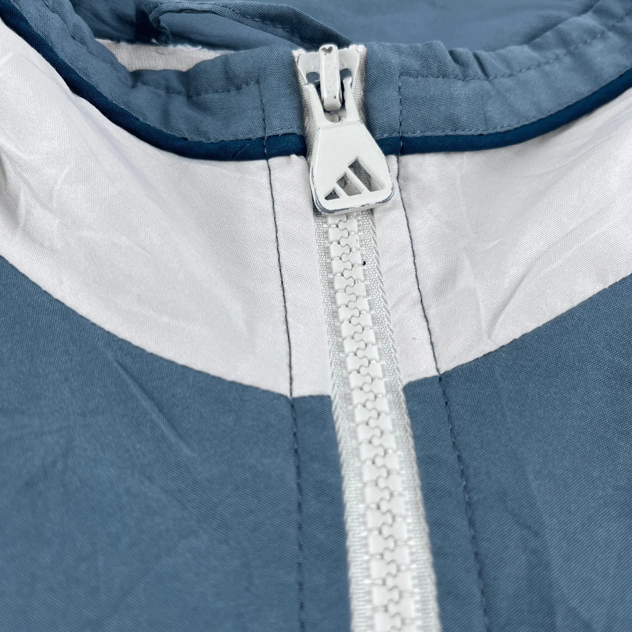 Nahaufnahme des Reißverschlusses einer Adidas Trainingsjacke Vintage 2000er in Blau und Weiß